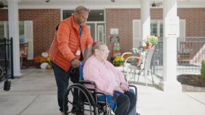 A male nurse is pushing a nursing home resident in a wheel chair outside at Alcoa Pines